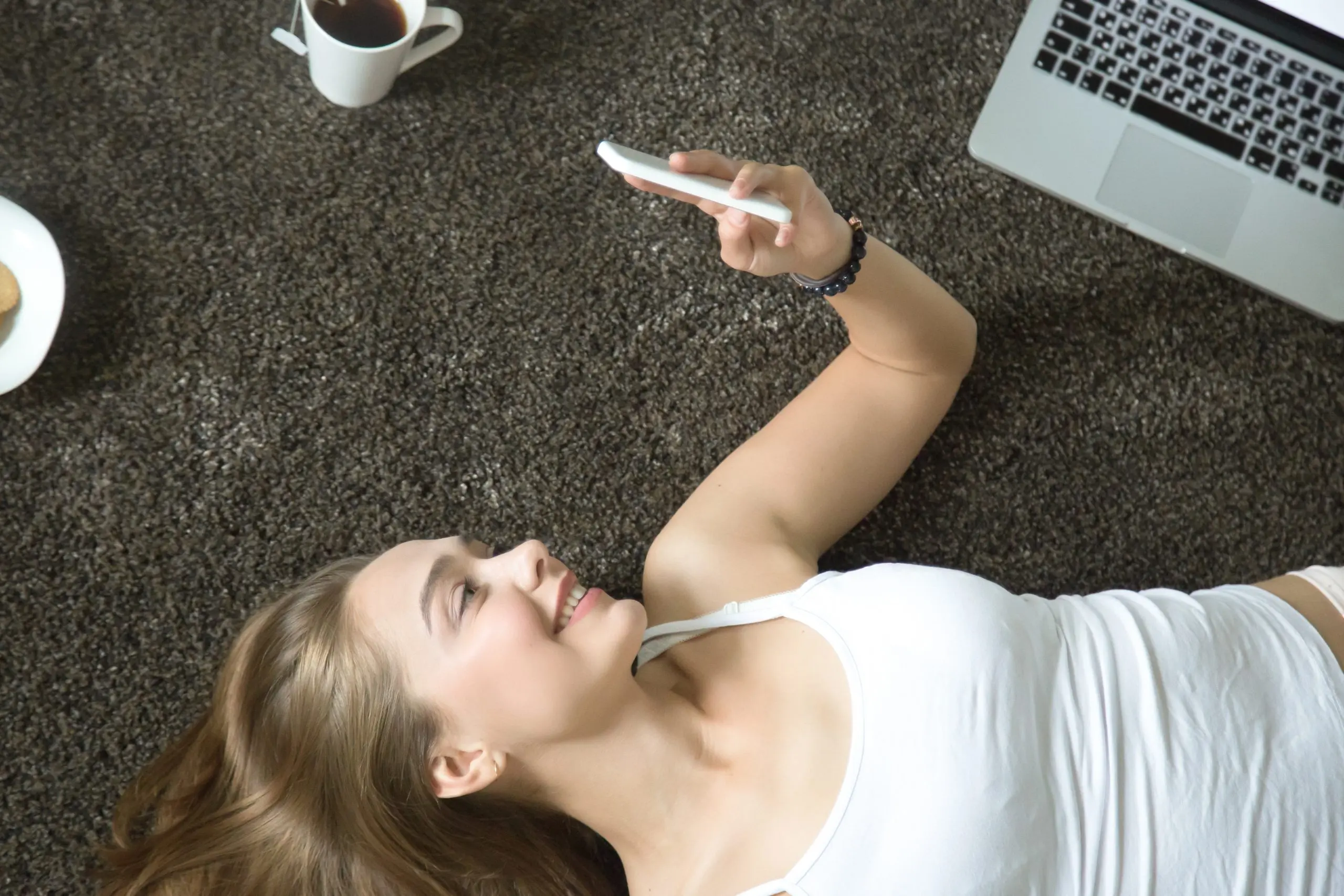 Woman lying on the carpet with a phone, thinking what digital detox is in everyday life
