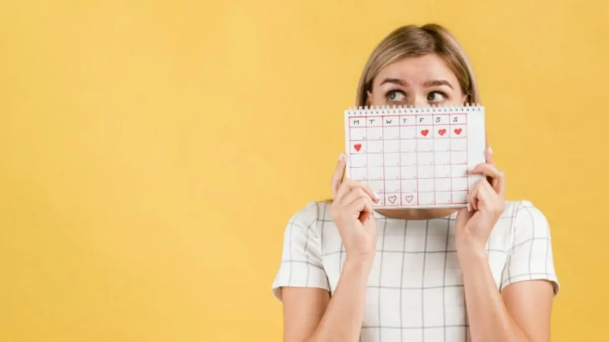 A woman holding a calendar and tracking her cycle